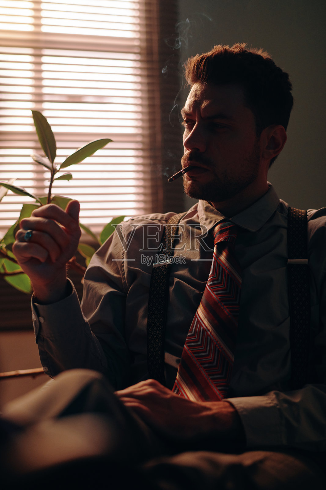 穿着正装的年轻人在办公室里抽烟照片摄影图片