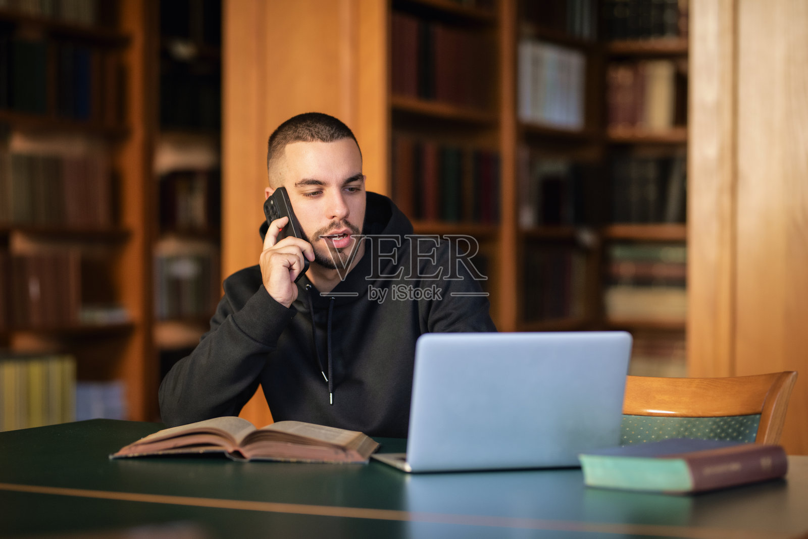 英俊的年轻人坐在大学图书馆学习照片摄影图片