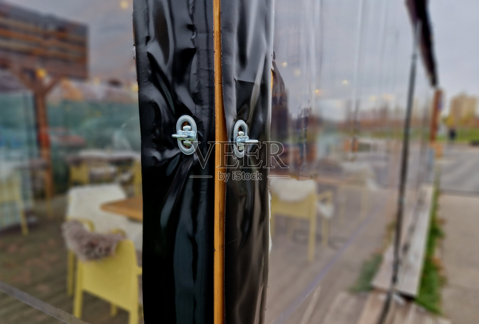 夏天座无虚席的餐馆的前花园在冬天就空了。解决方案是用透明的定制箔覆盖藤架。可由燃气燃烧器加热。角落里,安装照片摄影图片