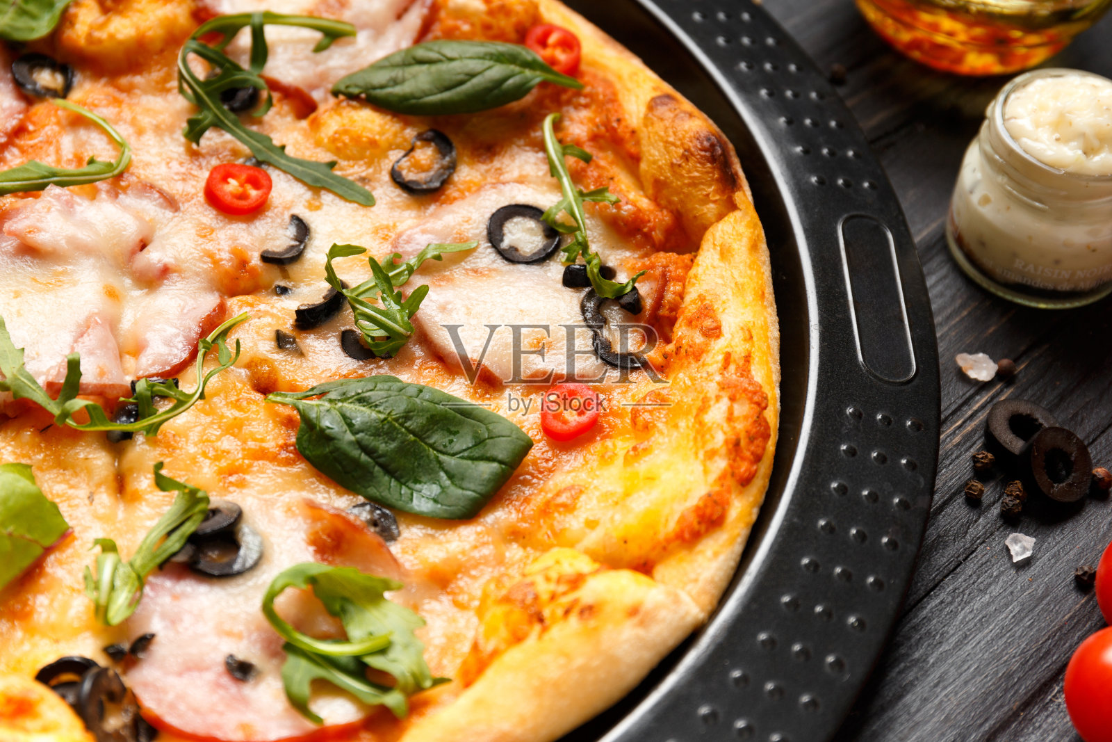 黑色木制背景上的烤盘上放着火腿披萨(俯视图)。照片摄影图片