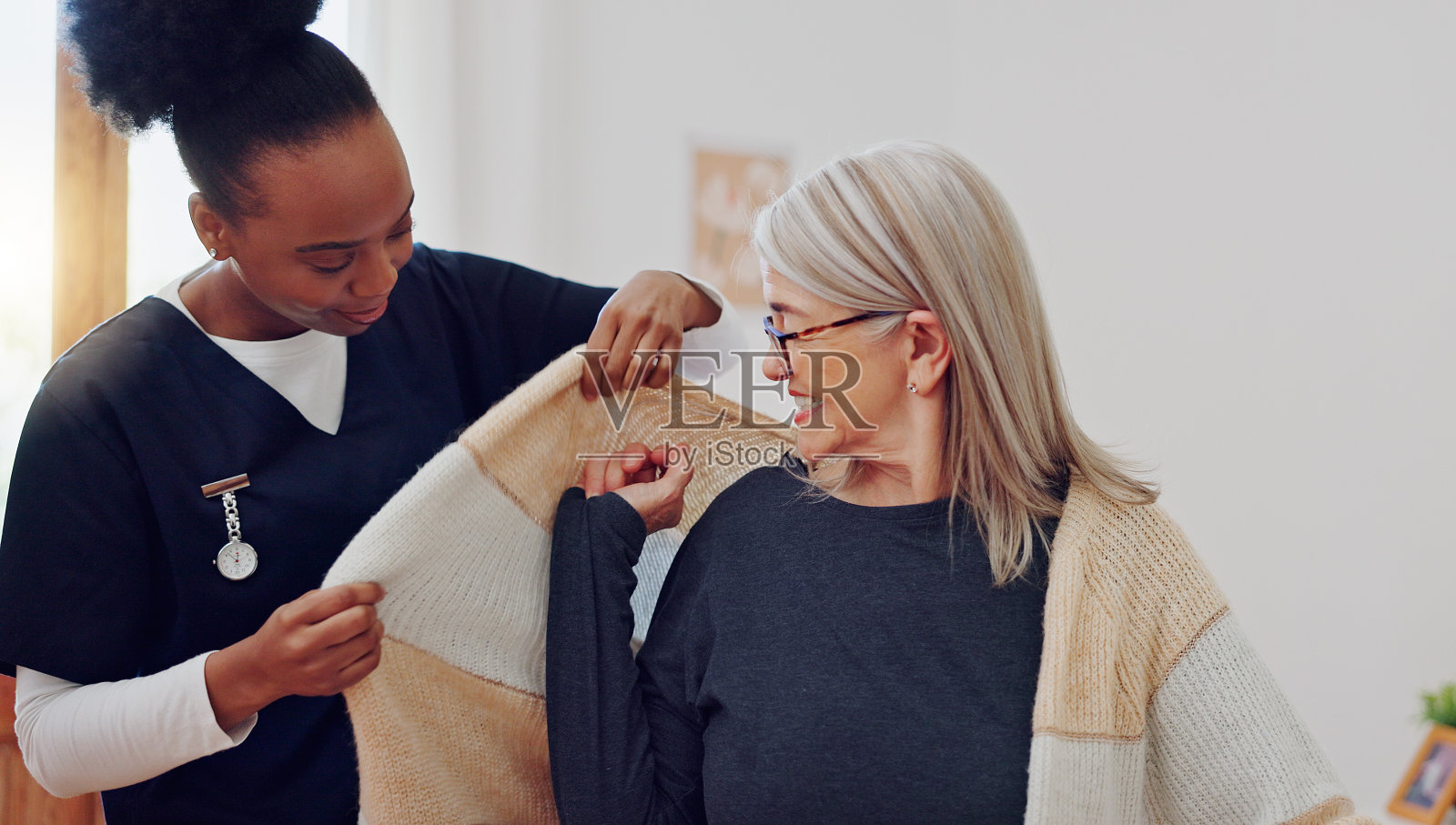 老年妇女，护理和帮助穿衣服，微笑和照顾退休，养老院和支持。非洲护工，老妇人，喜欢穿衣，喜欢辅助生活，爱和房子照片摄影图片