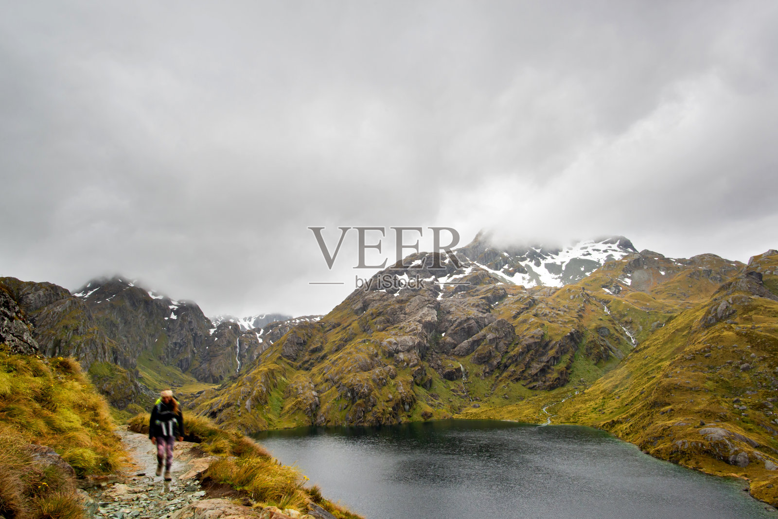 哈里斯湖与雪山的景色和徒步旅行者在Routeburn，新西兰的山顶照片摄影图片