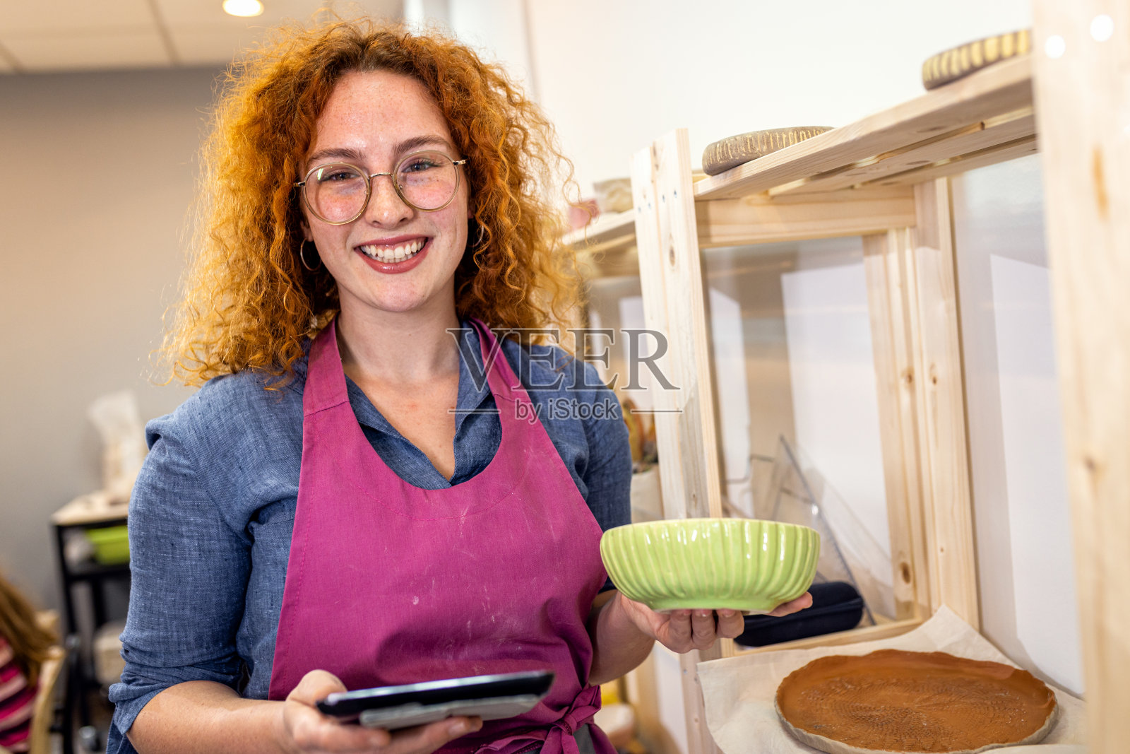 陶器工作室的女老板正在检查平板设备上的库存。照片摄影图片
