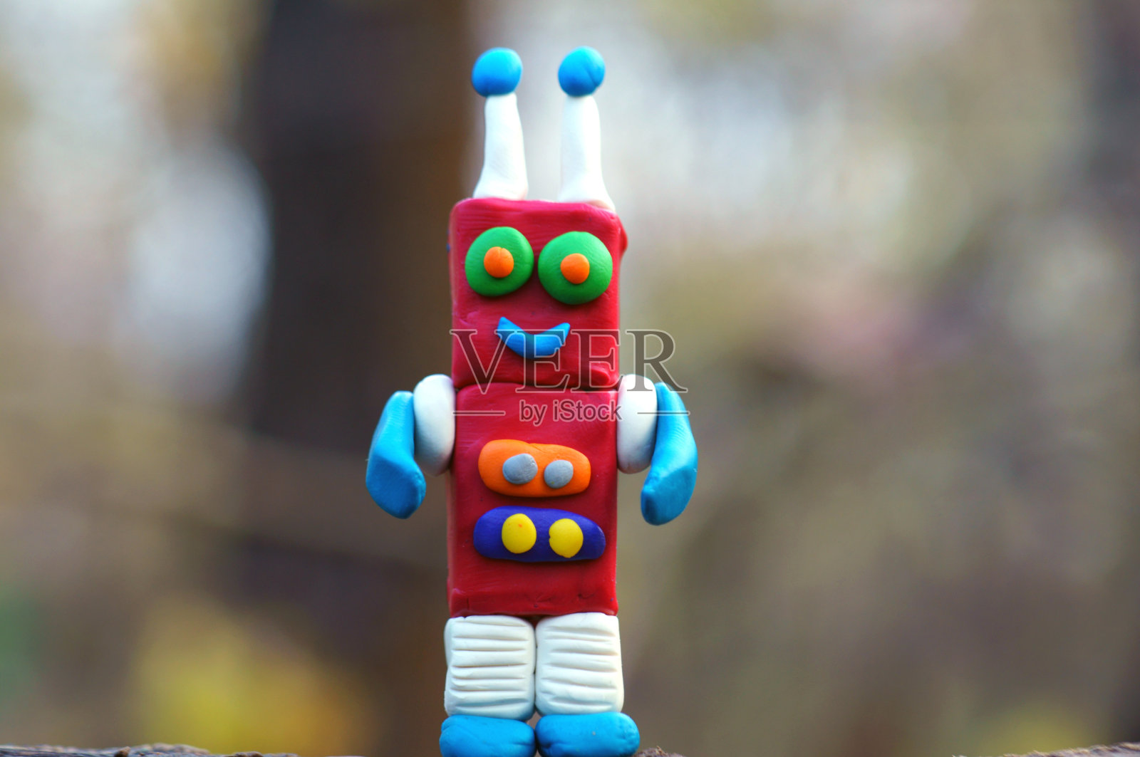 一个用橡皮泥做的玩具机器人在微笑。照片摄影图片