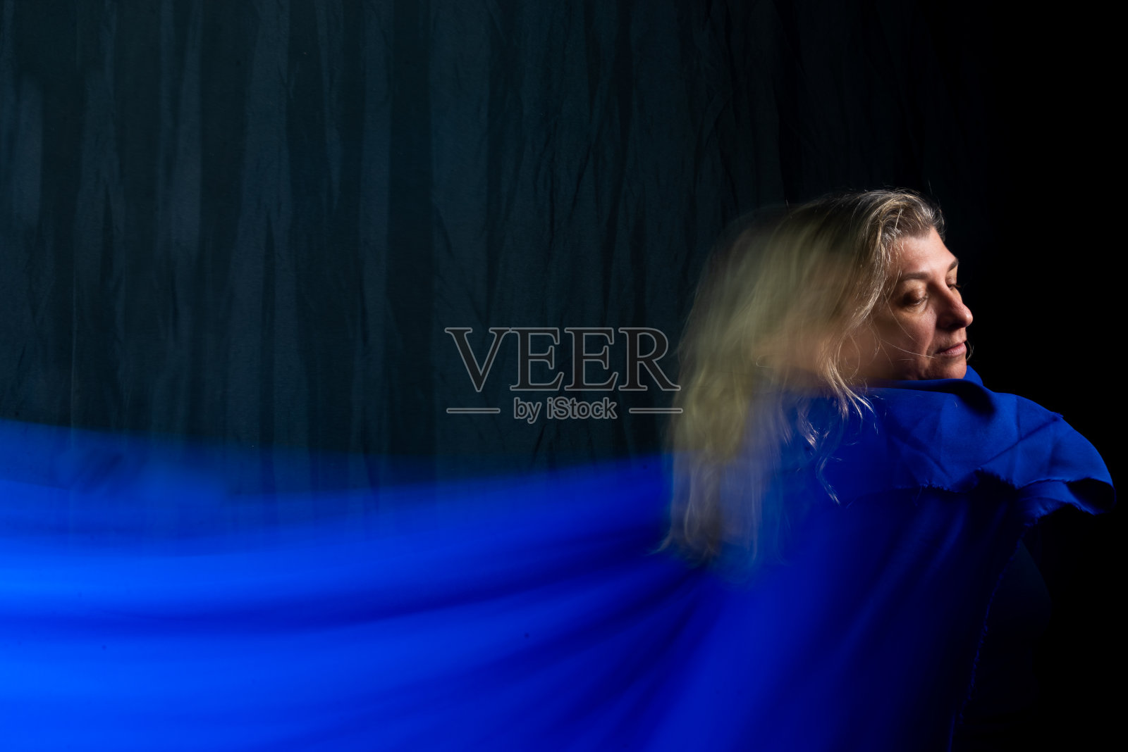 女舞者用蓝色布料做抽象表演。照片摄影图片