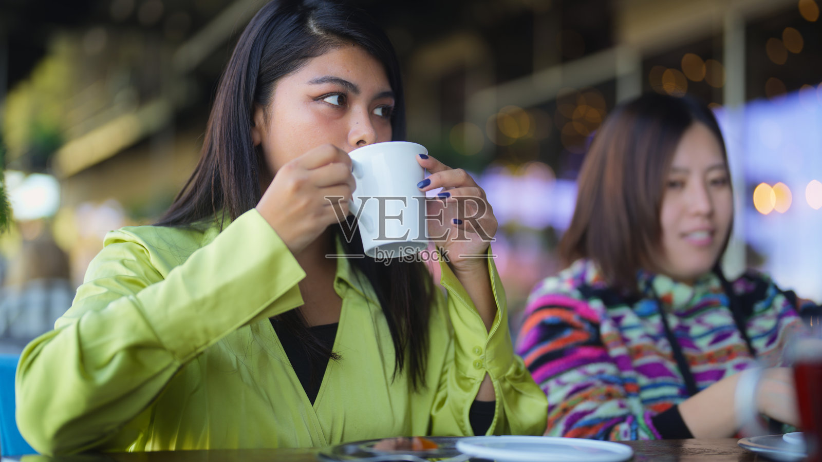 两个多民族女游客朋友在旅行途中在咖啡馆喝热饮照片摄影图片