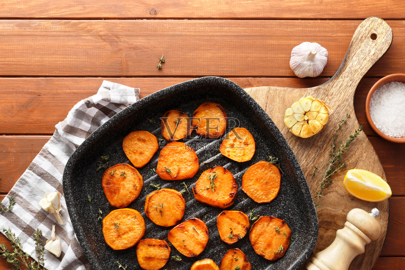 美味的烤红薯在煎锅里，食材放在木桌上照片摄影图片