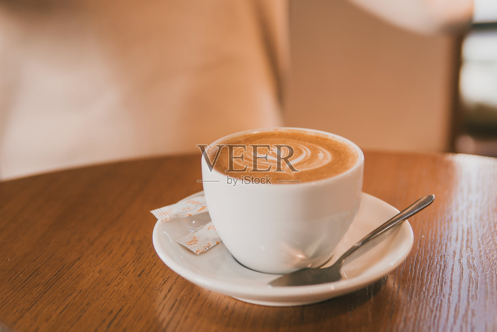 一个女孩在木桌旁喝拿铁咖啡。照片摄影图片