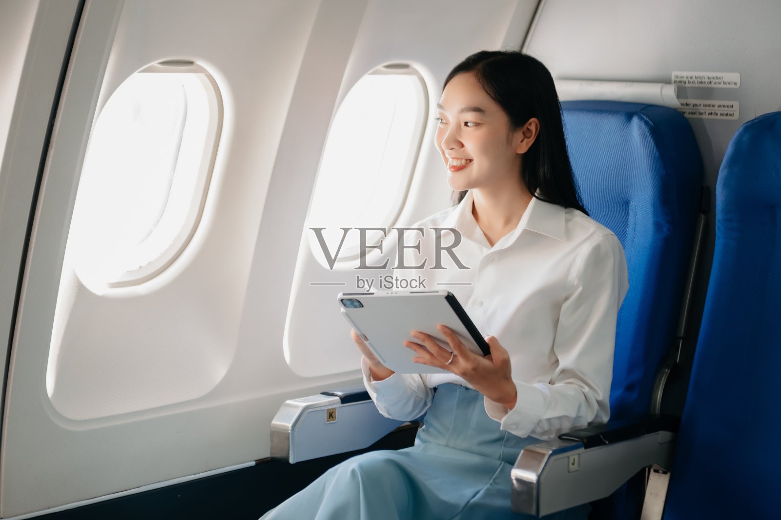 年轻的亚洲高管擅长于头等舱，使用平板电脑、笔记本电脑和智能手机进行多任务处理。时尚旅行，工作照片摄影图片