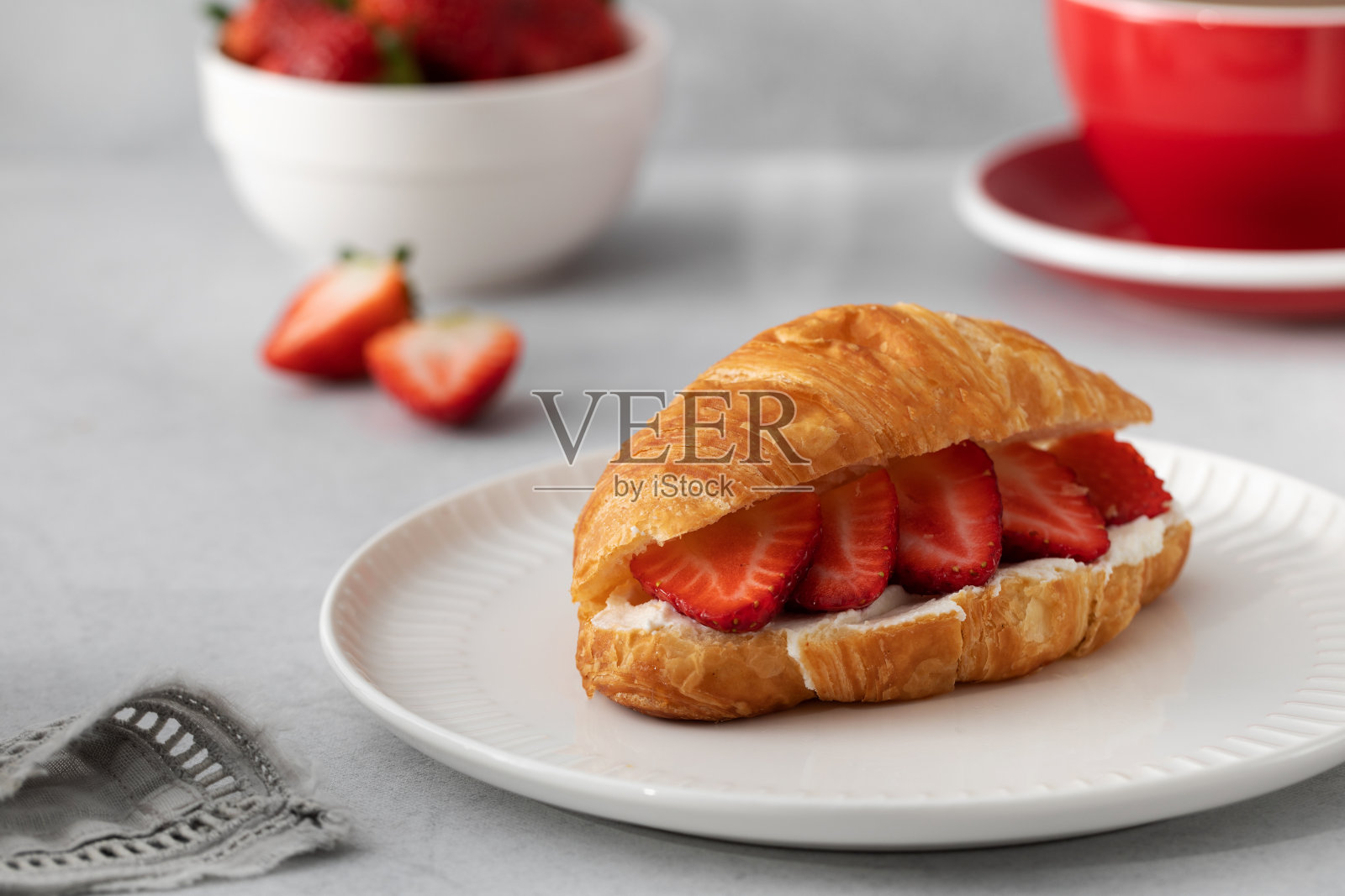 新鲜羊角面包配乳清干酪和新鲜草莓。牛角包加黑咖啡。照片摄影图片