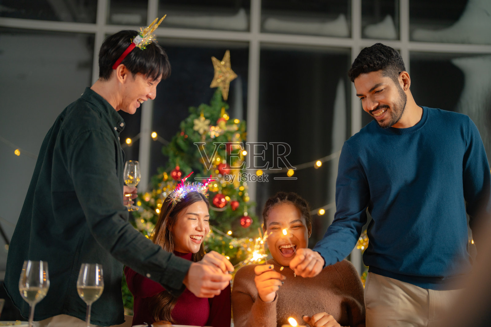 男男女女在一个有圣诞树的聚会上拿着烟花。年轻夫妇亚洲人喜欢庆祝圣诞节和新年。欢天喜地，用美食、美酒和友谊为爱庆祝;照片摄影图片
