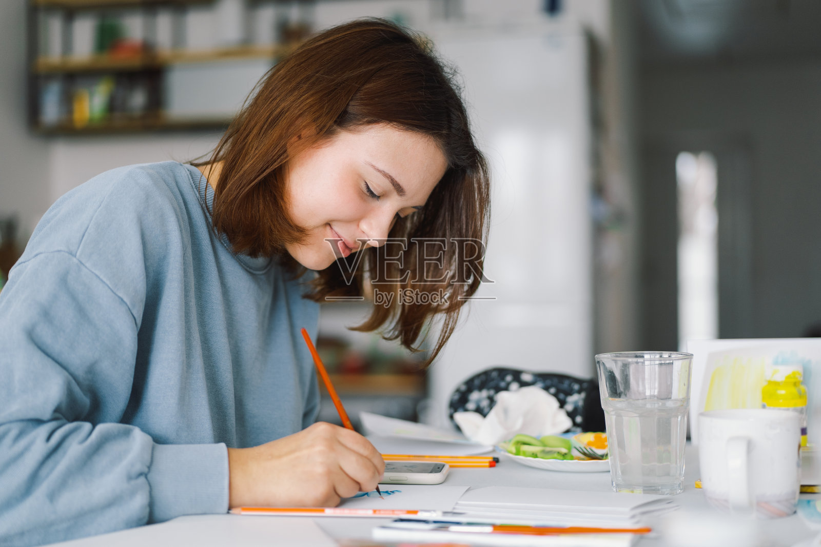 十几岁的女孩用彩色纸制作雪人卡片。照片摄影图片