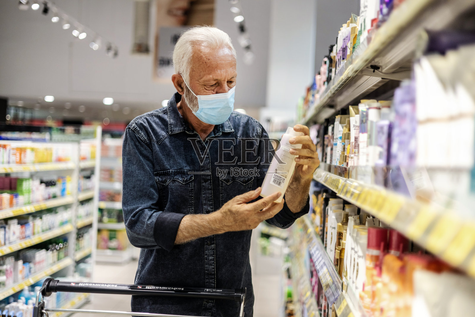戴着防护口罩的老人，在超市挑选化妆品，复印空间。照片摄影图片