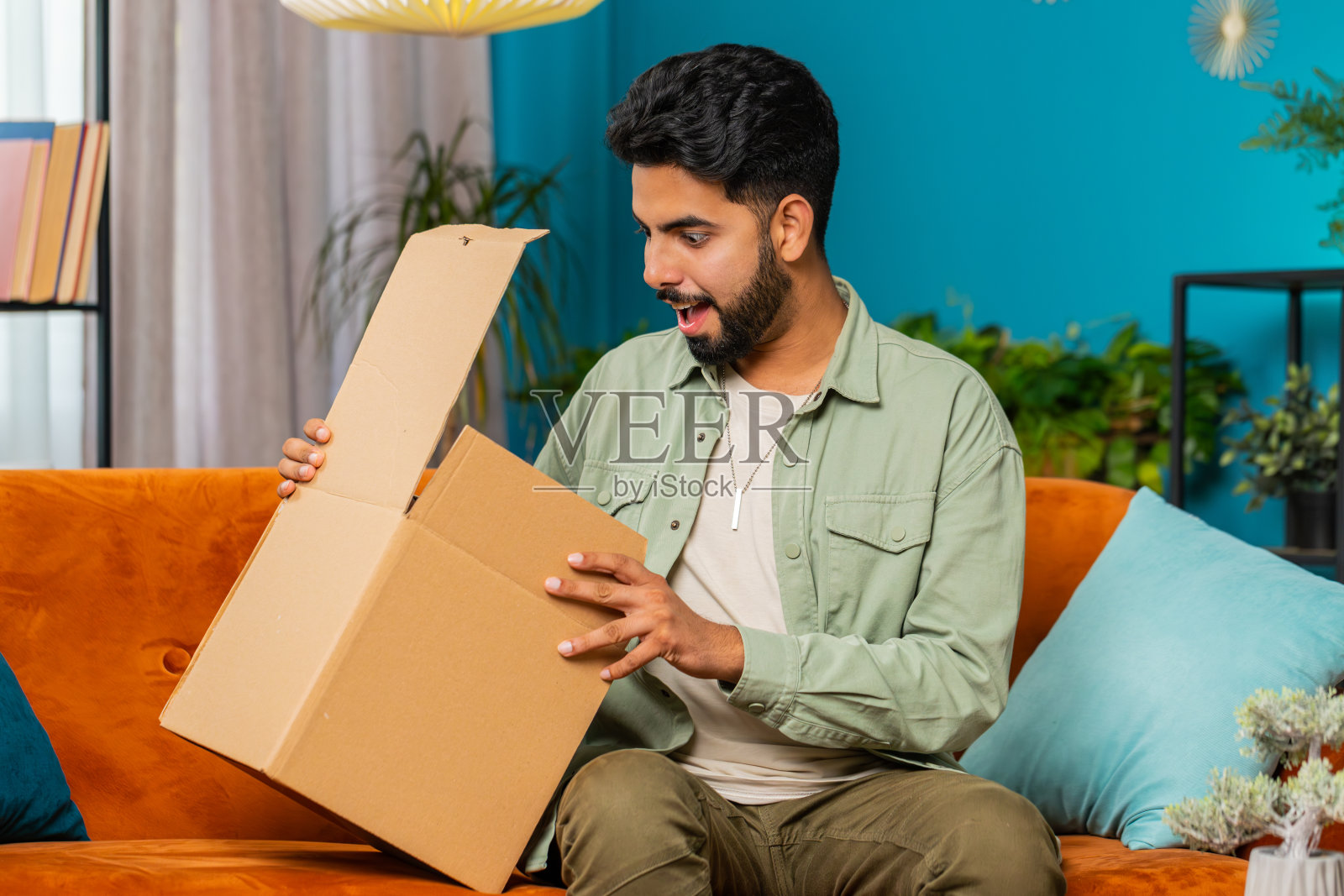 快乐的阿拉伯男子购物者打开纸板箱送货包裹网上购物购买在家里照片摄影图片