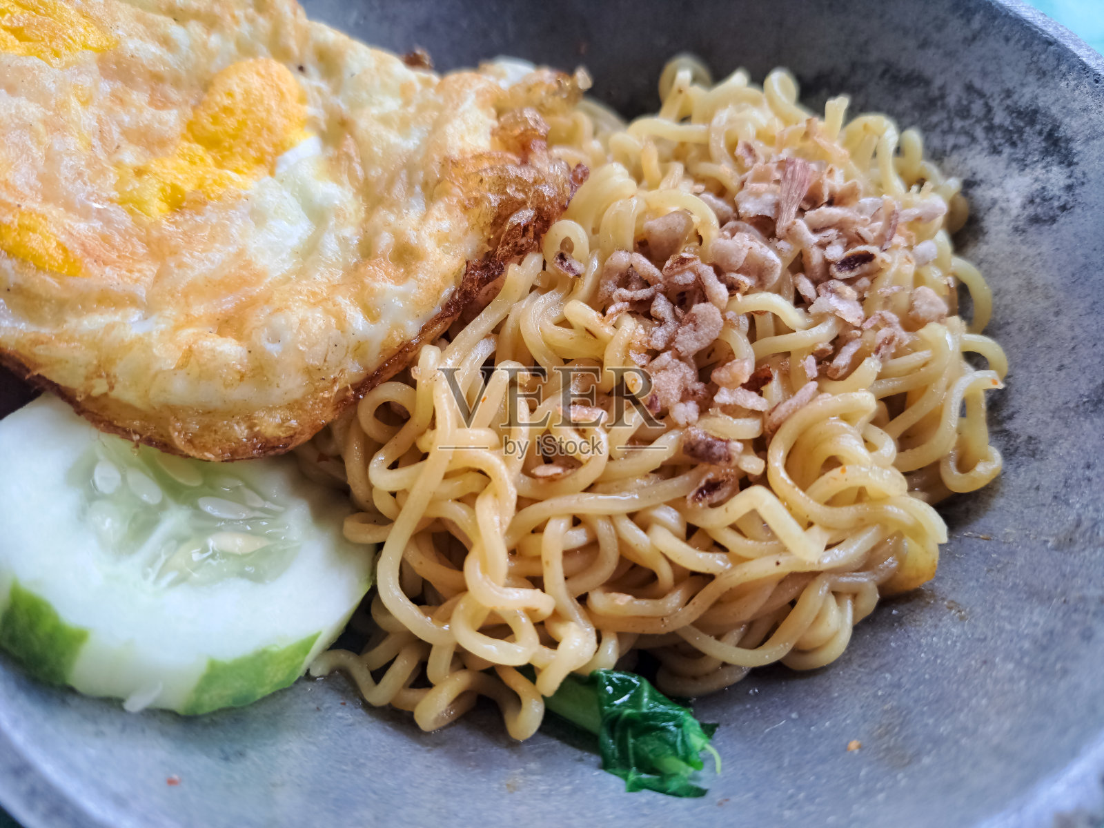 炒面配煎蛋，绿芥末，黄瓜片，炒洋葱。炒面，鸡蛋，芥菜，黄瓜片和炒洋葱撒在锅里。照片摄影图片