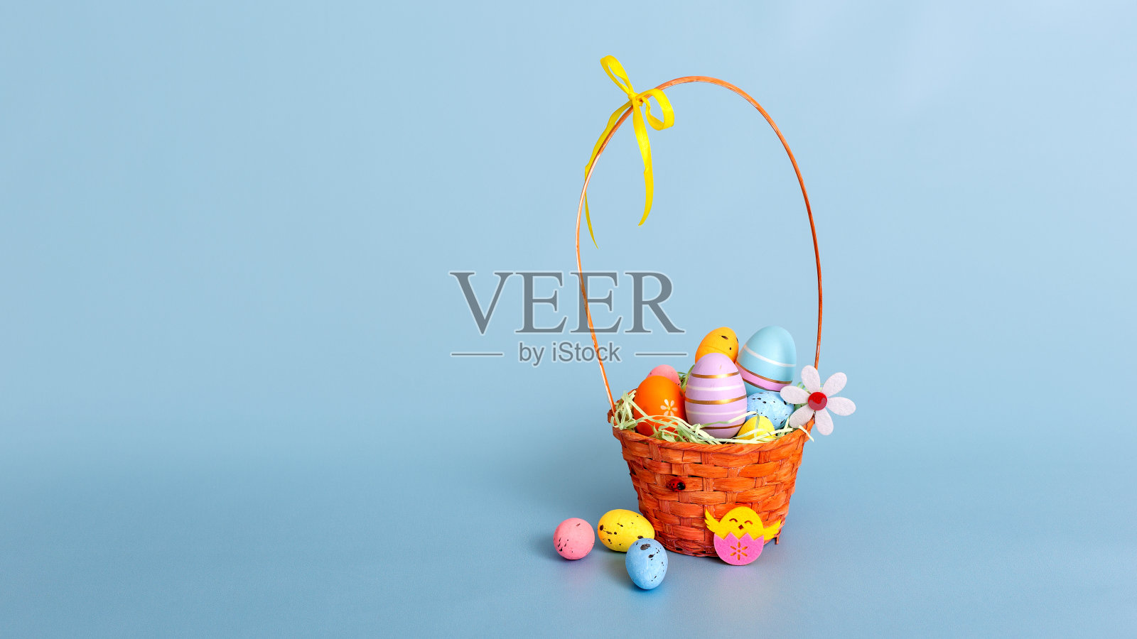 复活节柳条篮子装满装饰多彩色鸡蛋在浅蓝色的背景照片摄影图片