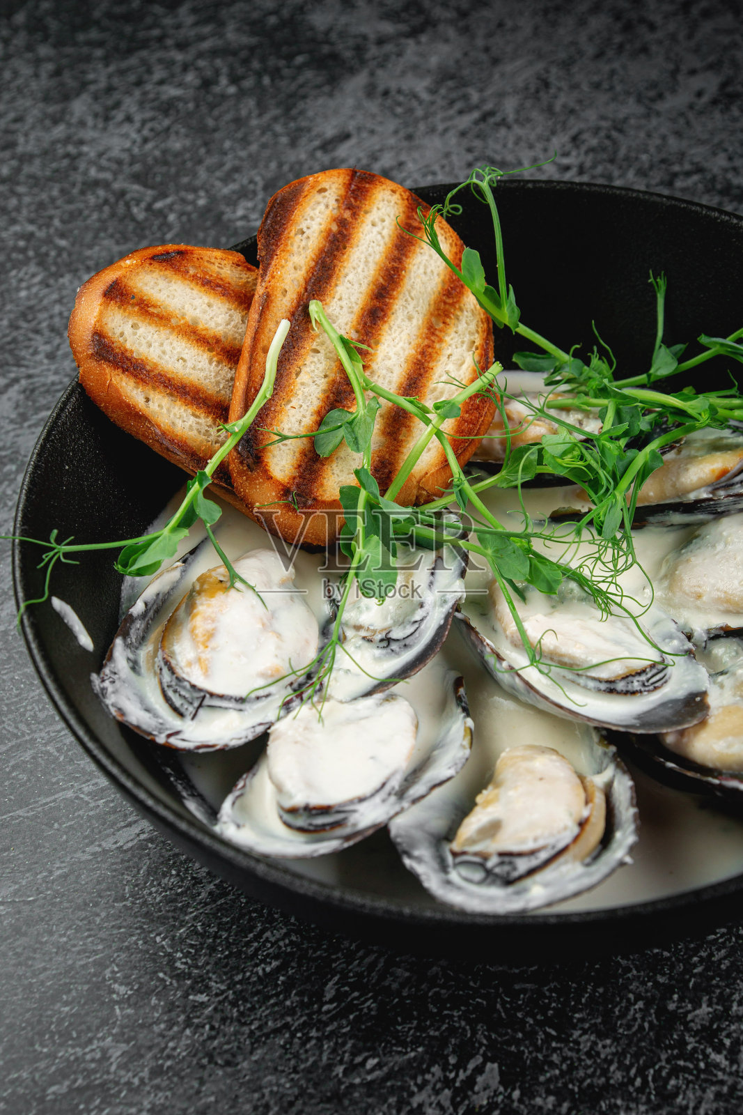 用深色盘子煎贻贝和面包丁照片摄影图片