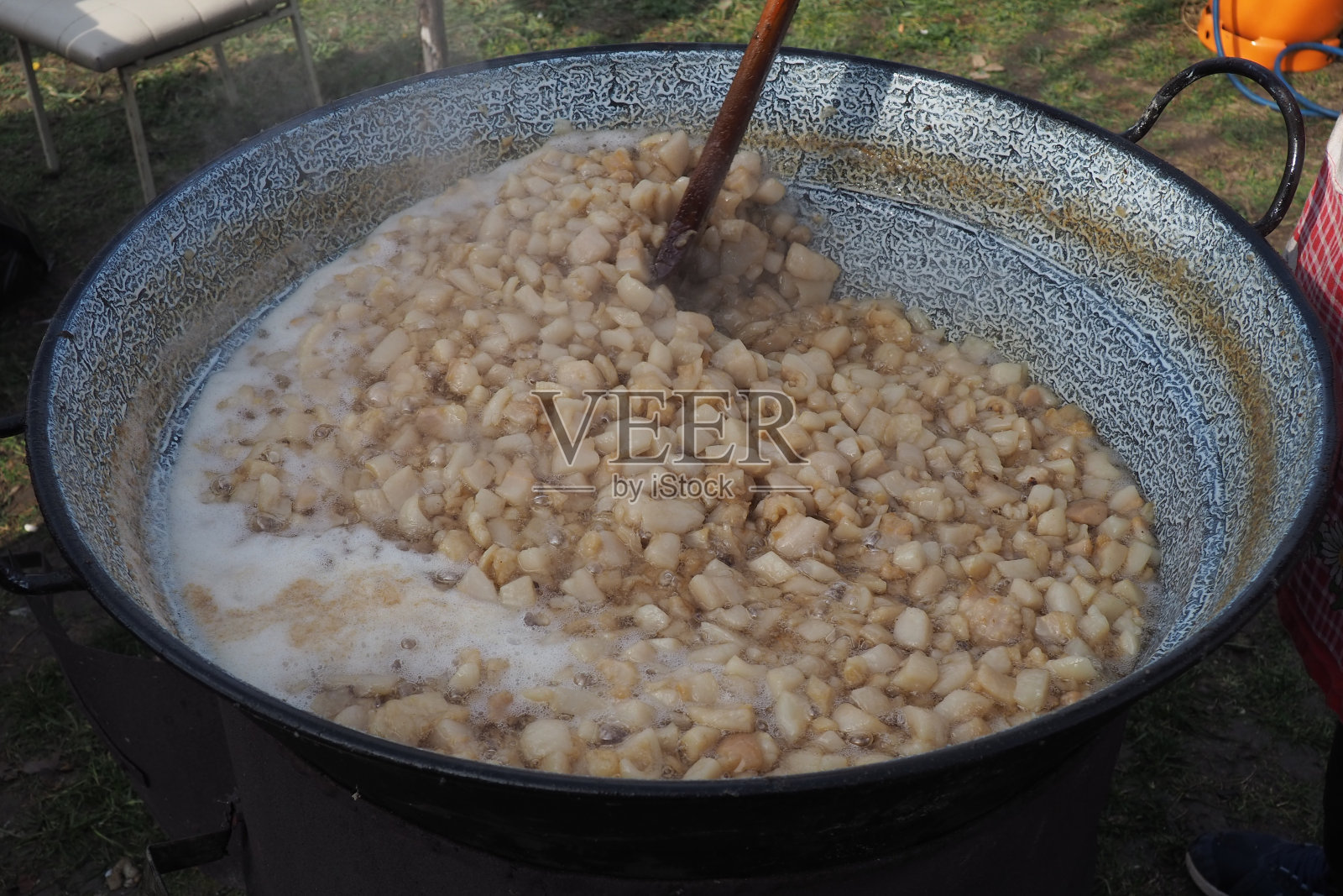 在大火上搅拌大桶中的油脂。猪皮是烹饪术语，指的是猪皮。它可以被渲染、油炸、烘烤、烤成小块的猪肉脆皮或猪皮照片摄影图片