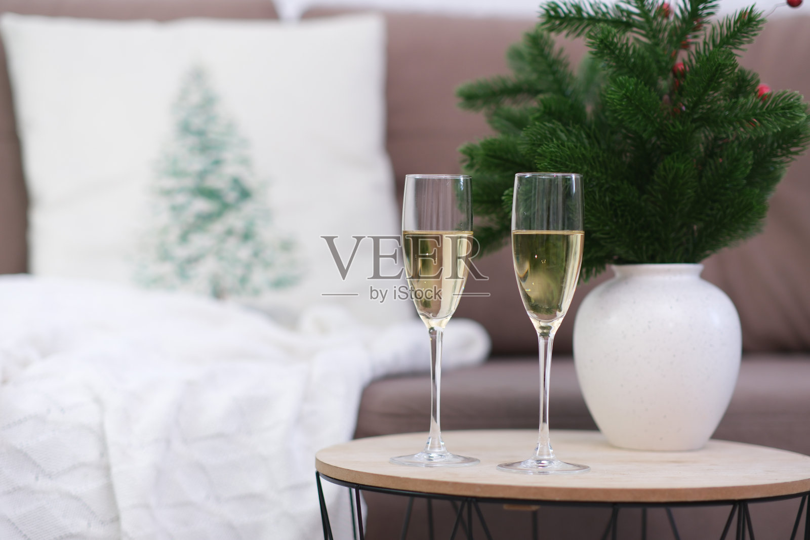 客厅咖啡桌上的两杯香槟。圣诞家庭内部。有冷杉枝的陶瓷花瓶。照片摄影图片