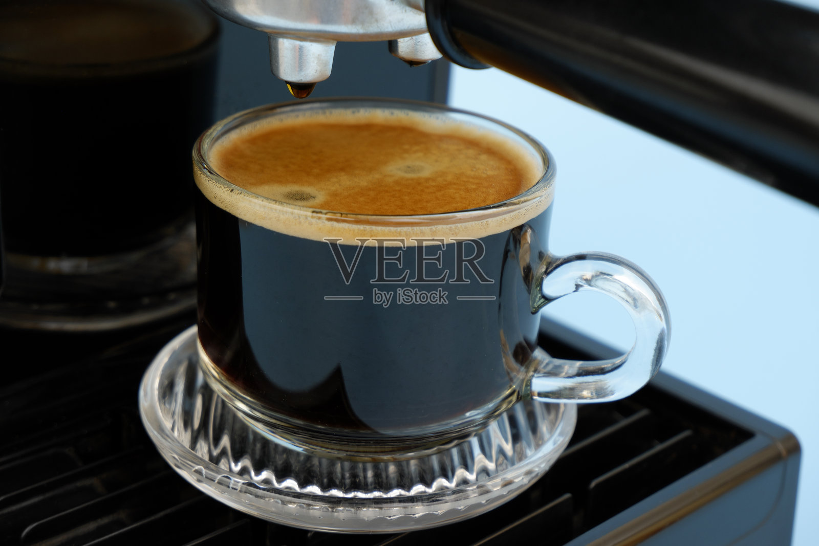 浓缩咖啡机与玻璃杯子在蓝色背景。照片摄影图片