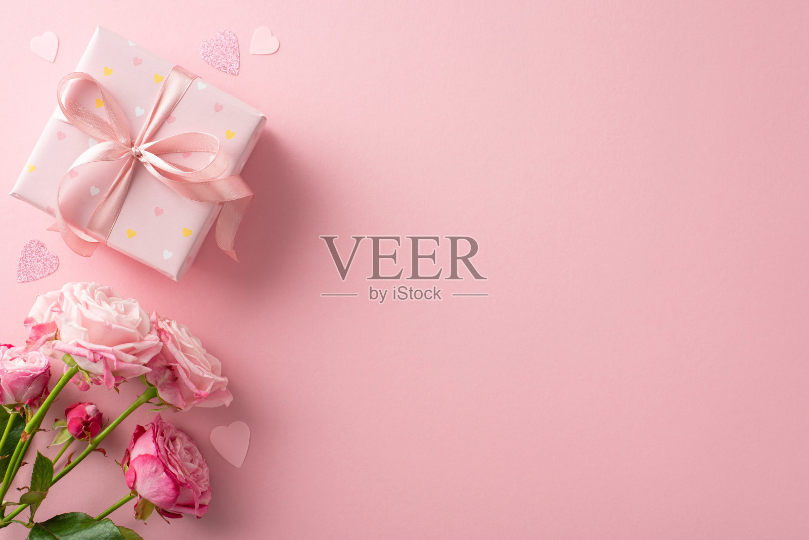 在情人节用这个俯视图显示创造一个浪漫的气氛。礼品盒，一束玫瑰，粉色背景的心形纸屑。文本空白照片摄影图片