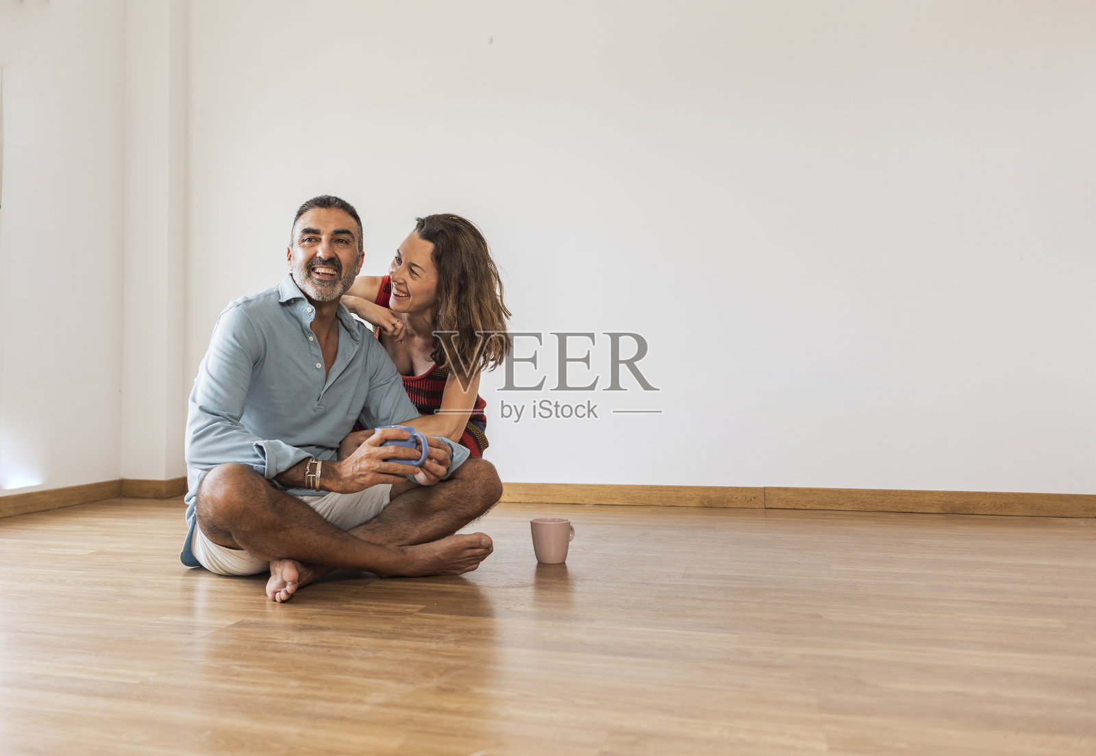 成熟的夫妇在空房子里喝咖啡，买房子，搬家。照片摄影图片