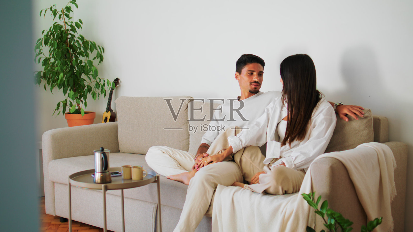 微笑的夫妇拥抱沙发特写。女人抚摸着男人的脸，一起放松照片摄影图片