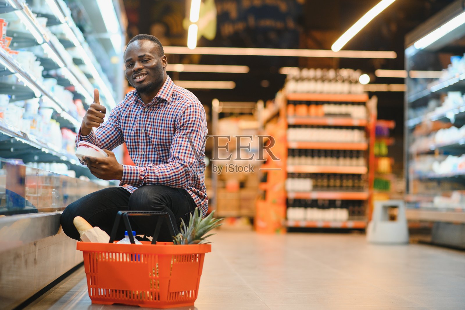 一名非洲男子在超市购物。帅哥拿着购物篮照片摄影图片