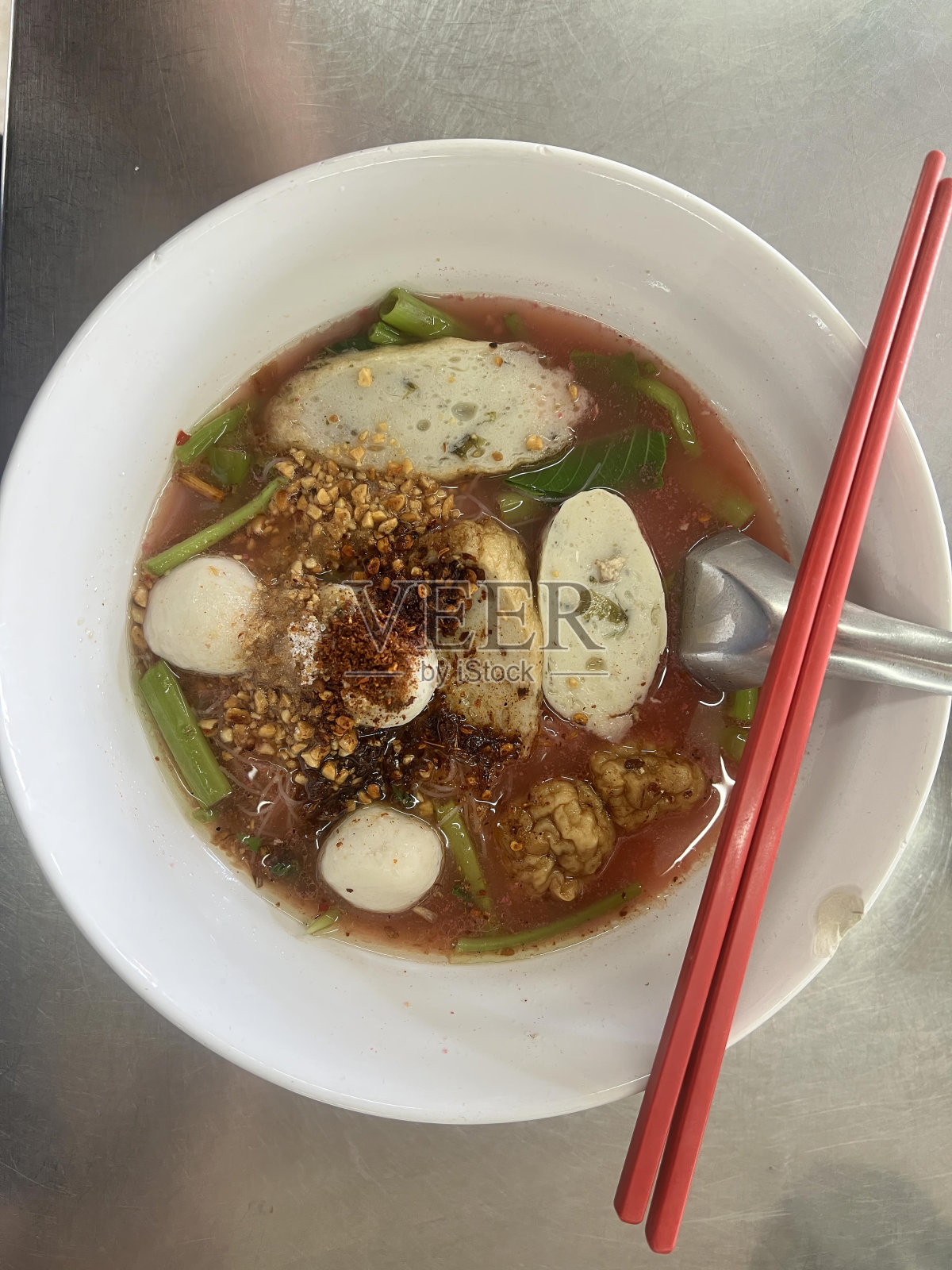 用筷子和勺子盛一碗汤的照片。照片摄影图片