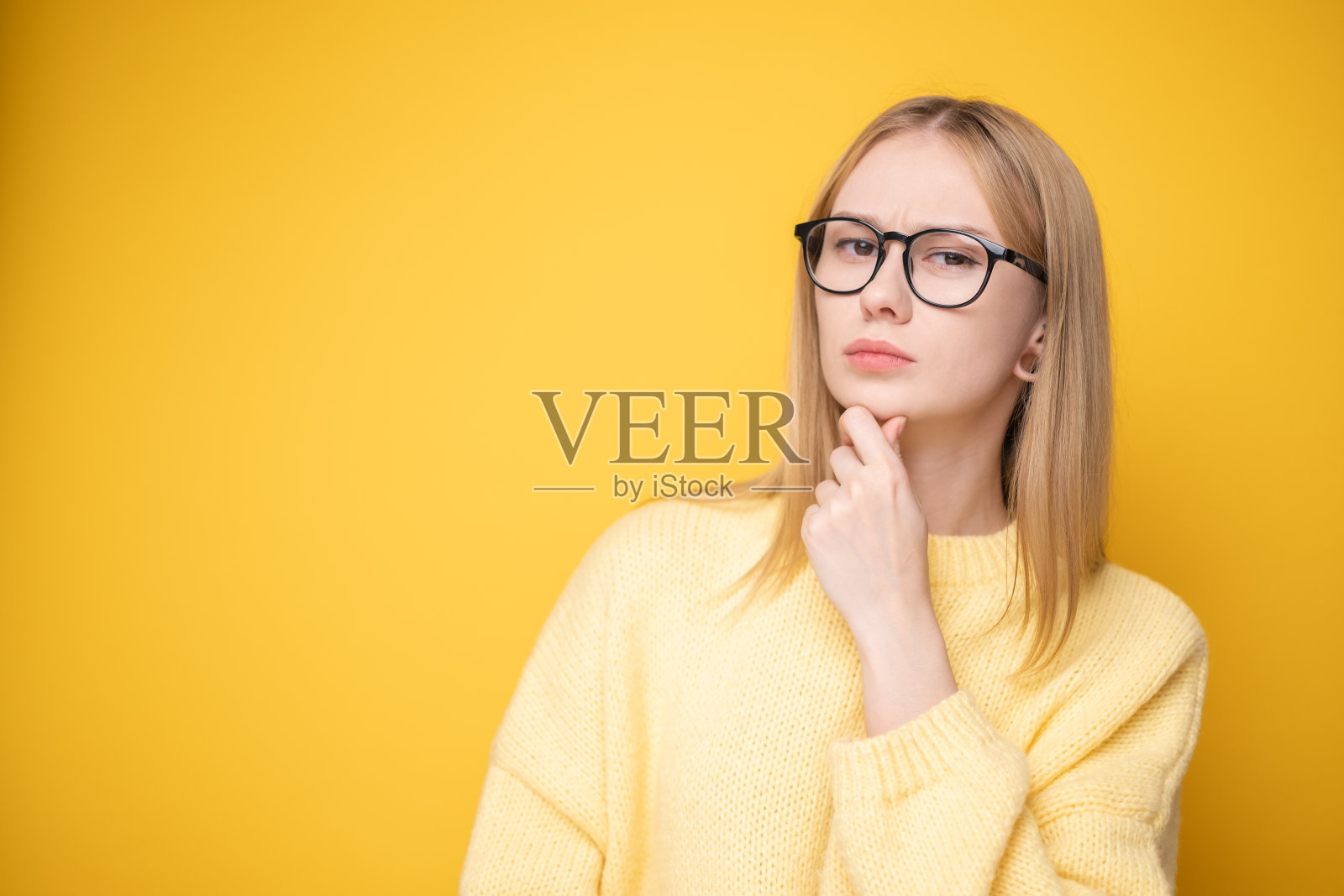 可爱的女孩在黄色背景上穿着毛衣和眼镜的肖像。横幅或广告布局。照片摄影图片