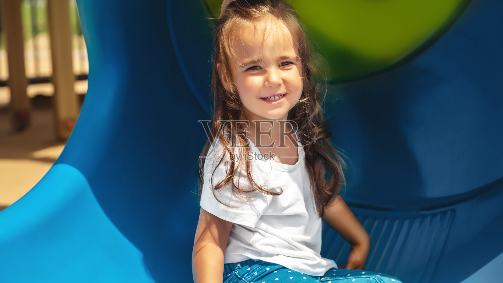 操场上活泼的小女孩。玩滑梯的孩子照片摄影图片