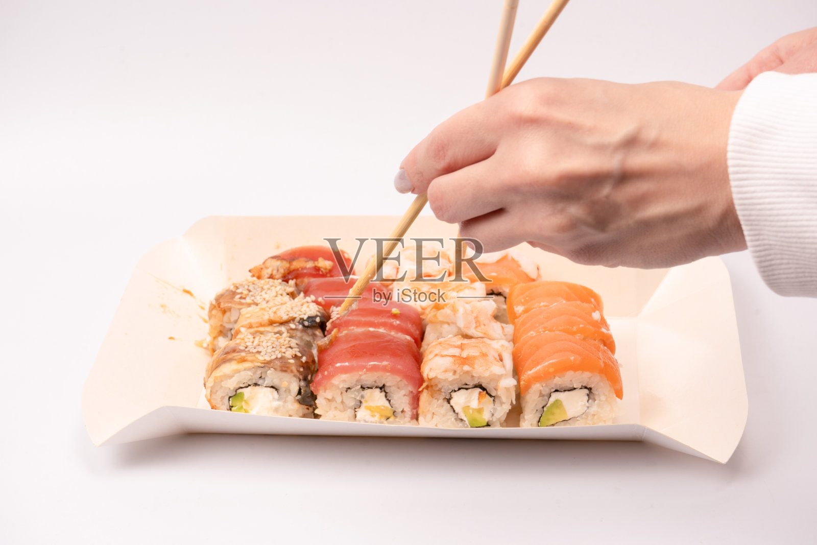 食品交付。一个女人手里拿着寿司卷的盒子被孤立了。照片摄影图片