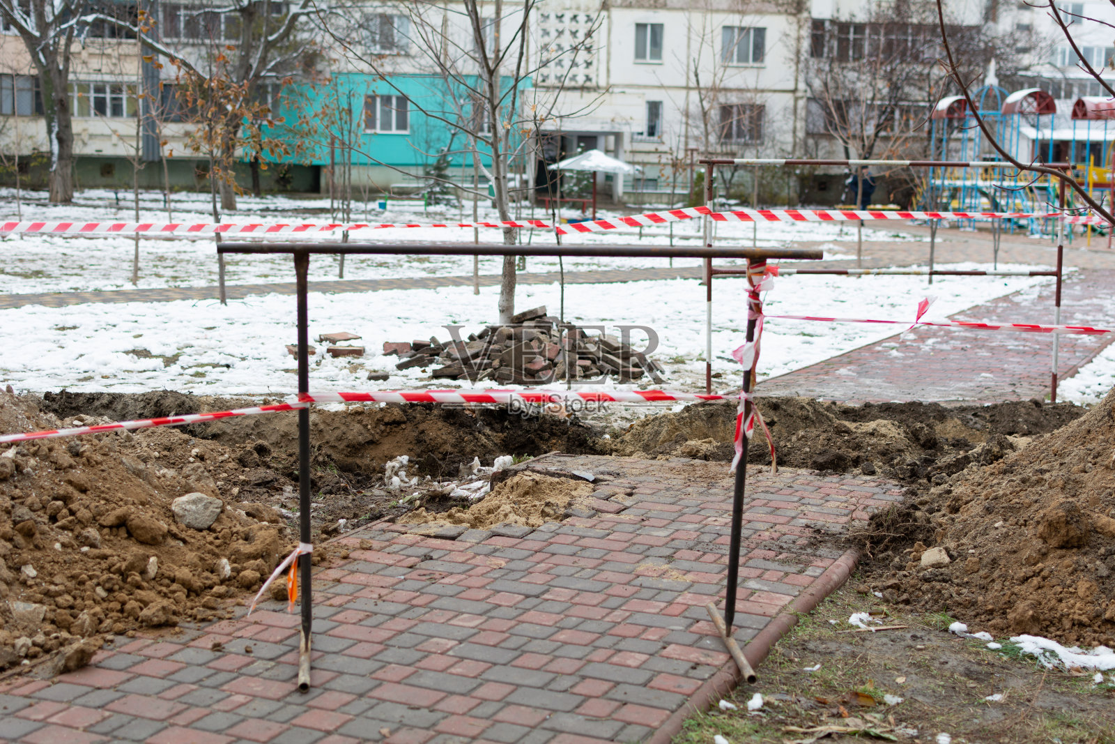 破损的铺路板、金属围栏和防护施工胶带。浅景深，选择性对焦照片摄影图片