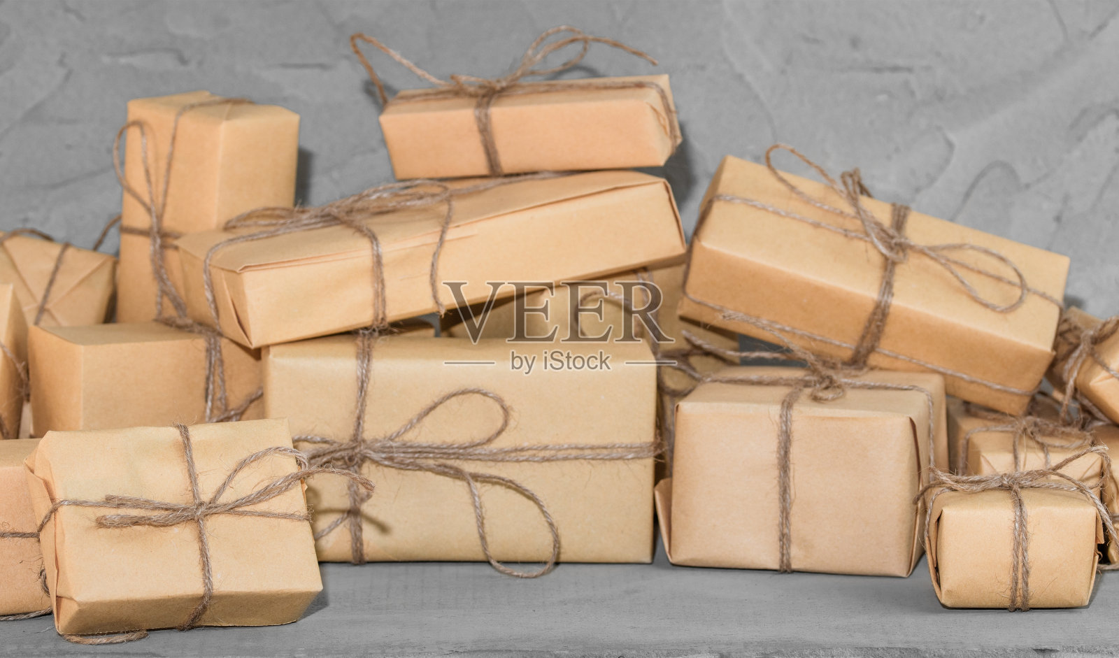 呈现在深灰色纹理表背景。用工艺纸装饰的棕色礼品盒。节日的背景。照片摄影图片