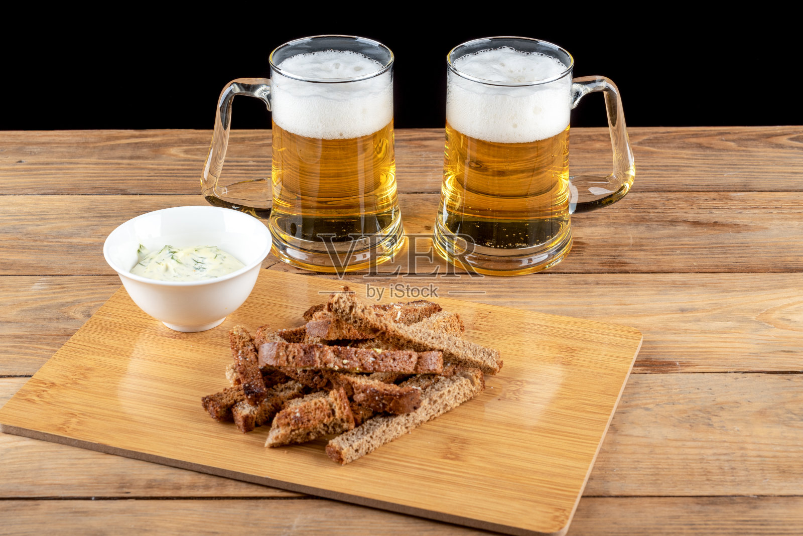 两个装着啤酒的杯子和木桌上美味的啤酒小吃。照片摄影图片