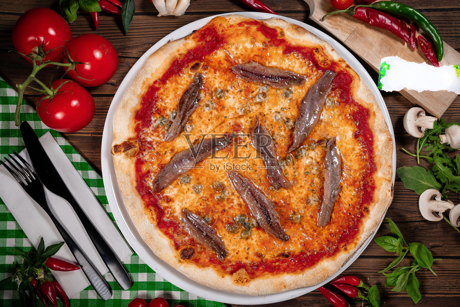 那不勒斯披萨配番茄凤尾鱼刺山柑靠近木桌照片摄影图片