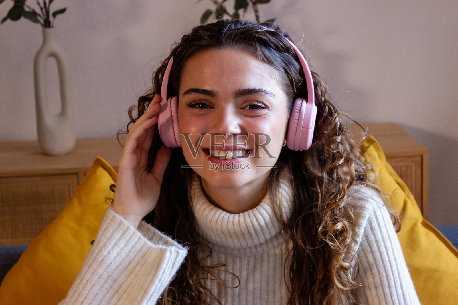 微笑的年轻女子戴着耳机在家听音乐的画像照片摄影图片