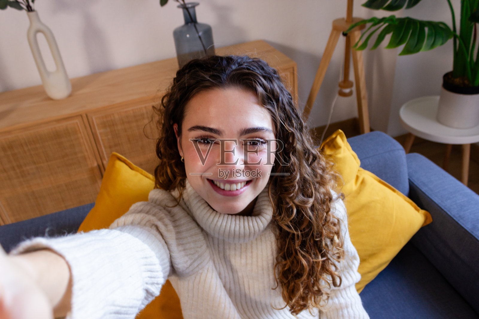 从高角度看，微笑的年轻女子在家里的沙发上自拍照片摄影图片