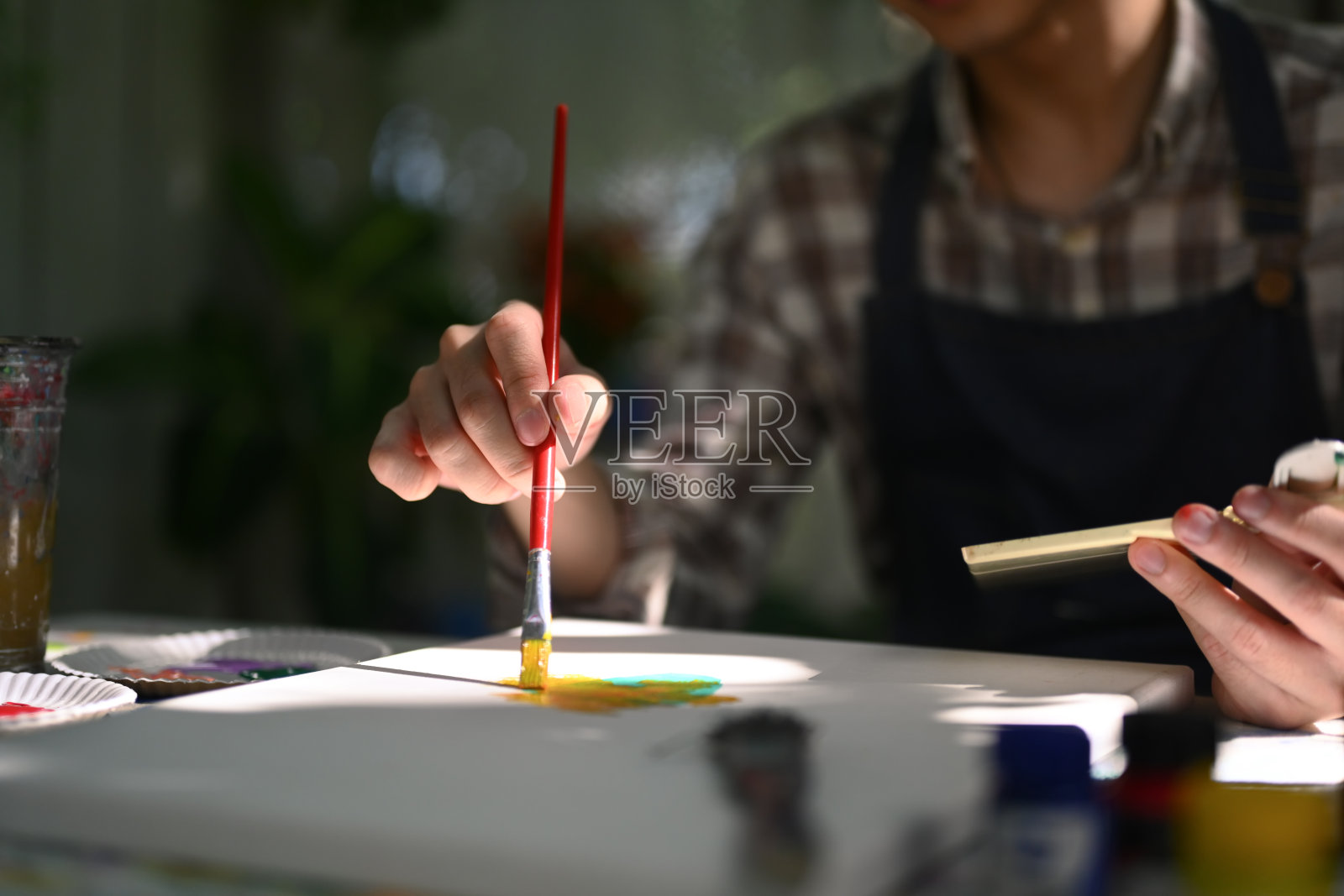 男艺术家在后院阳光下在帆布上作画的剪影。照片摄影图片