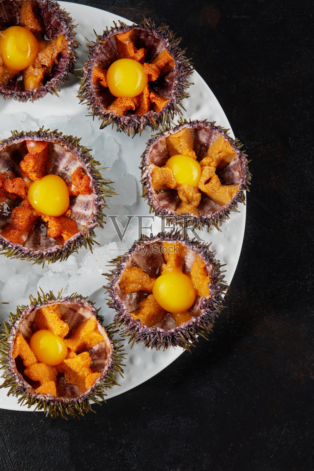 海胆放在陶瓷碗里，加冰。鹌鹑蛋酱油海胆菜。照片摄影图片