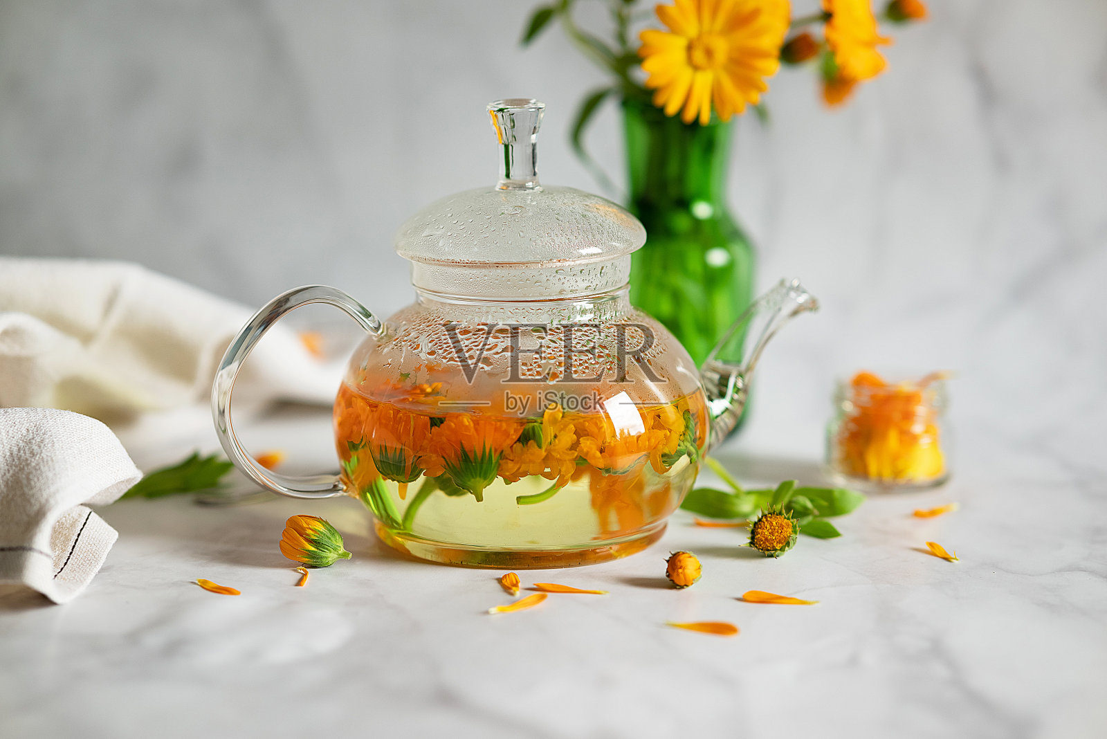 一杯万寿菊茶和室外绿色背景下的金盏花。照片摄影图片