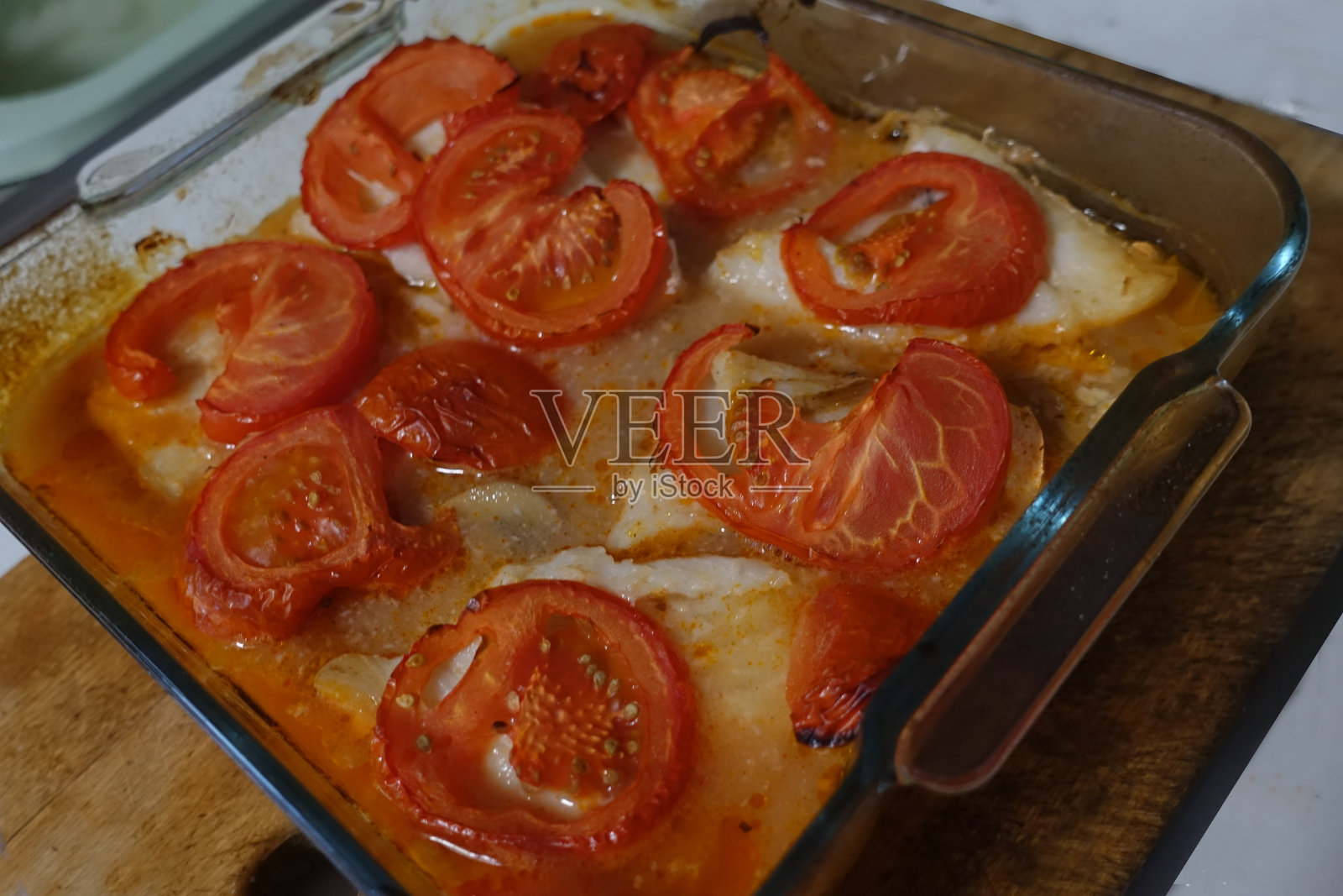 用白葡萄酒、西红柿和蘑菇在烤箱里煮鳕鱼照片摄影图片