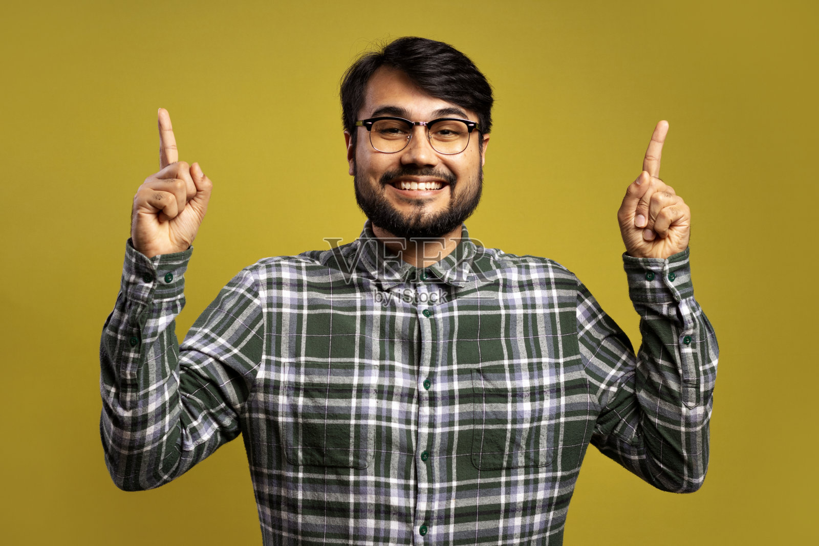 男人微笑着用两只手指着上面照片摄影图片