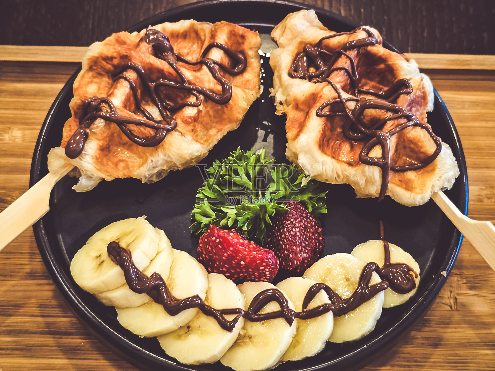 华夫饼上面撒上巧克力和新鲜草莓。照片摄影图片