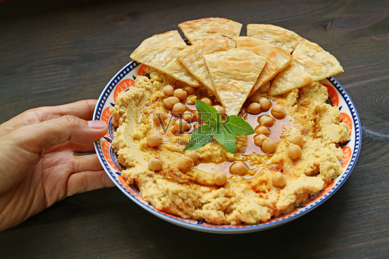 用手将新鲜制作的鹰嘴豆泥和皮塔饼放在木桌上照片摄影图片