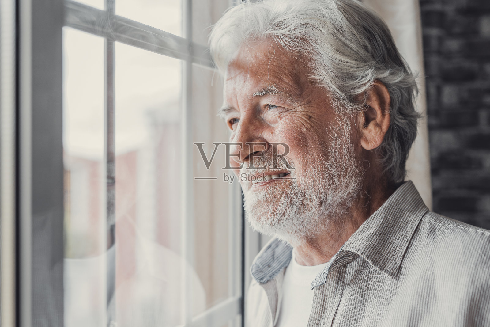 快乐体贴的70多岁老人满怀希望地望着窗外，想着身体健康、退休、保险福利，梦想着未来。领取退休金的长者等候与家人会面照片摄影图片