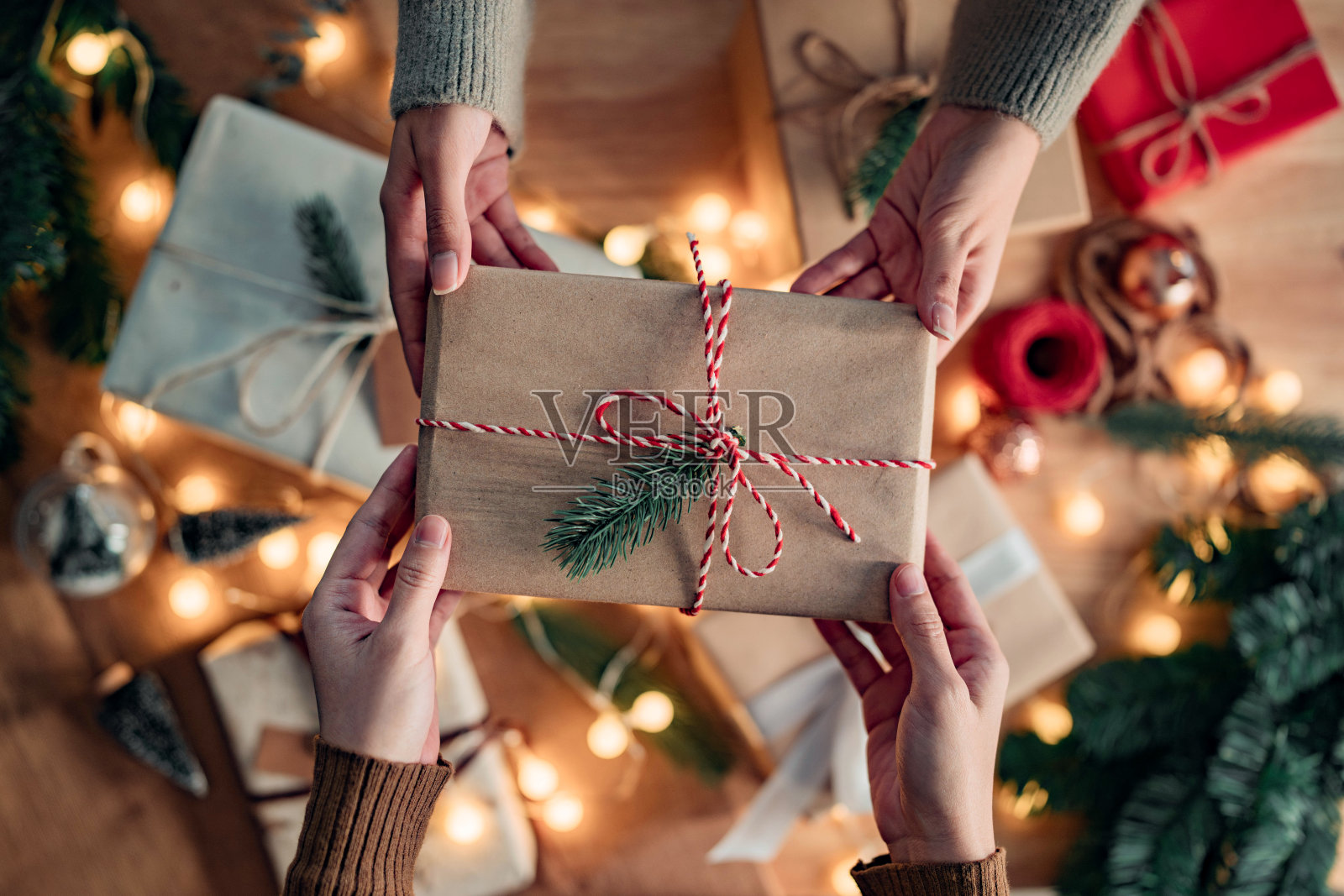 俯视图-妇女的手得到惊喜手工圣诞礼物从她的女朋友在圣诞装饰背景，给礼物，圣诞快乐，节日快乐!照片摄影图片