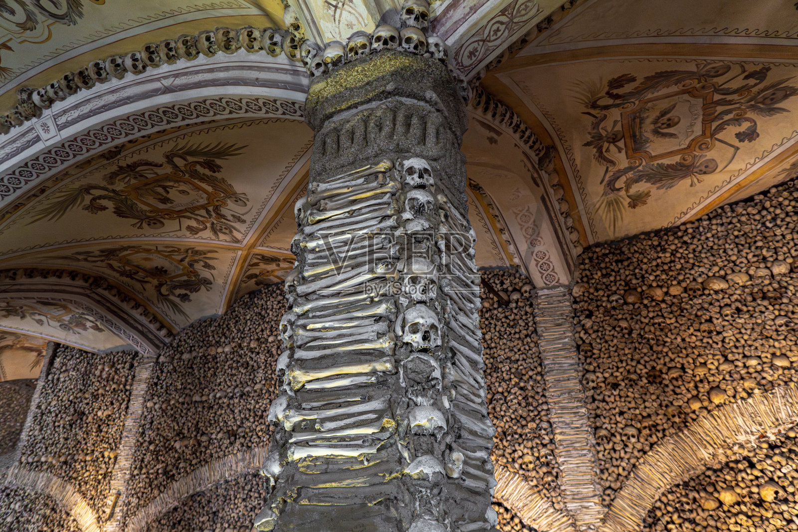 柱子上装饰着人类的骨头和头骨，拱形的天花板上画着来自骨头教堂的宗教寓言画。葡萄牙埃武拉。照片摄影图片