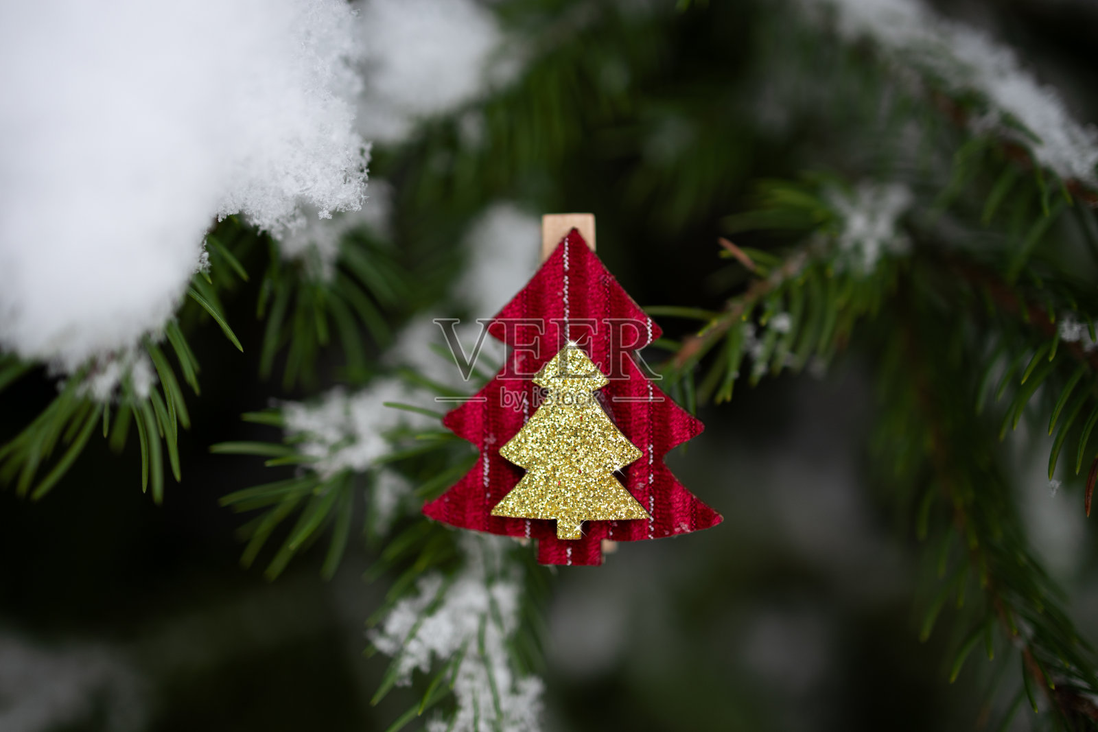 户外被雪覆盖的圣诞树树枝上，红色的冷杉形状的圣诞装饰品照片摄影图片