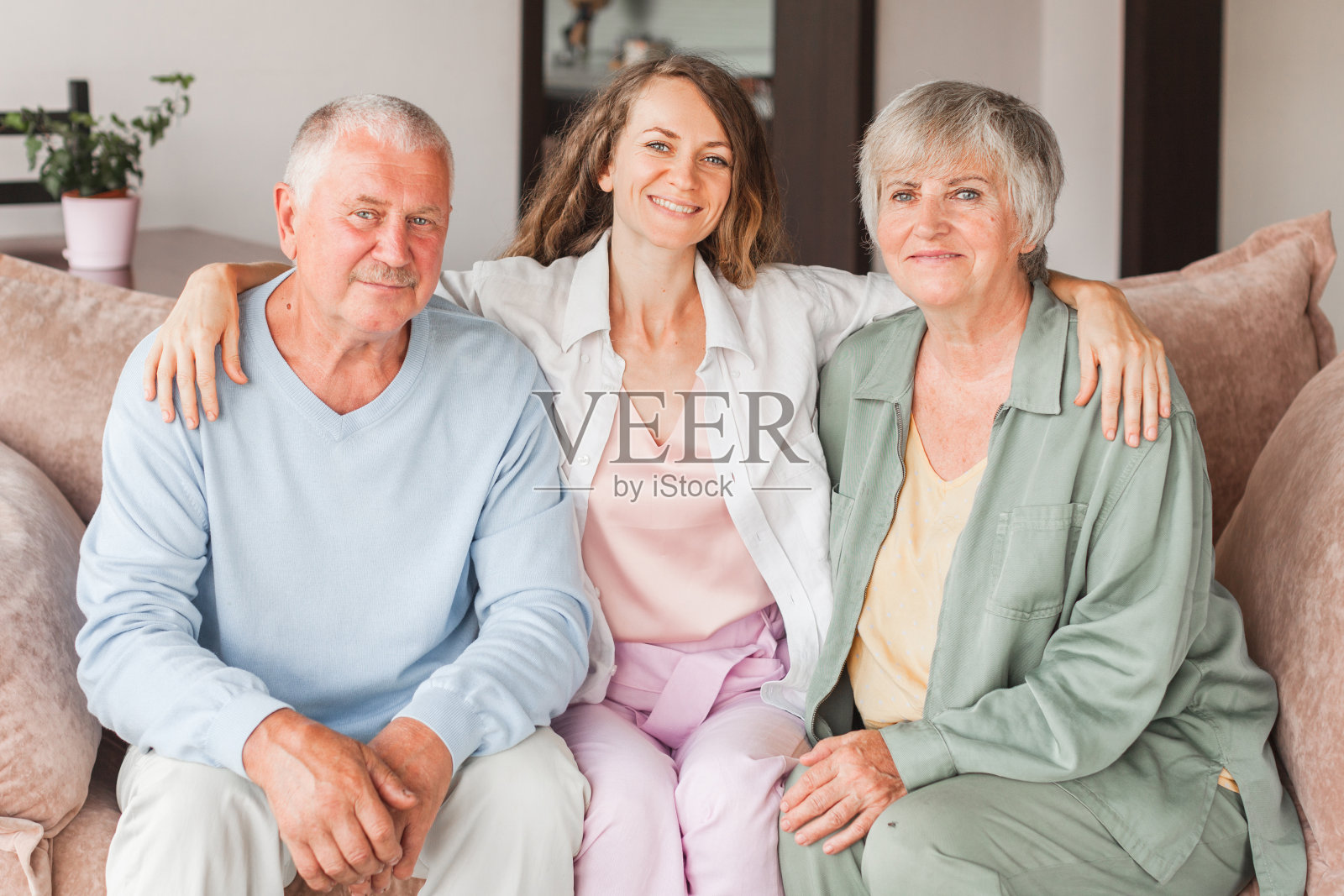 不同世代的家人依偎在沙发上，在家里一起享受时光，和爸爸妈妈一起笑着长大的女儿照片摄影图片